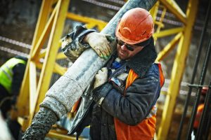 Construction worker carrying an industrial pipe